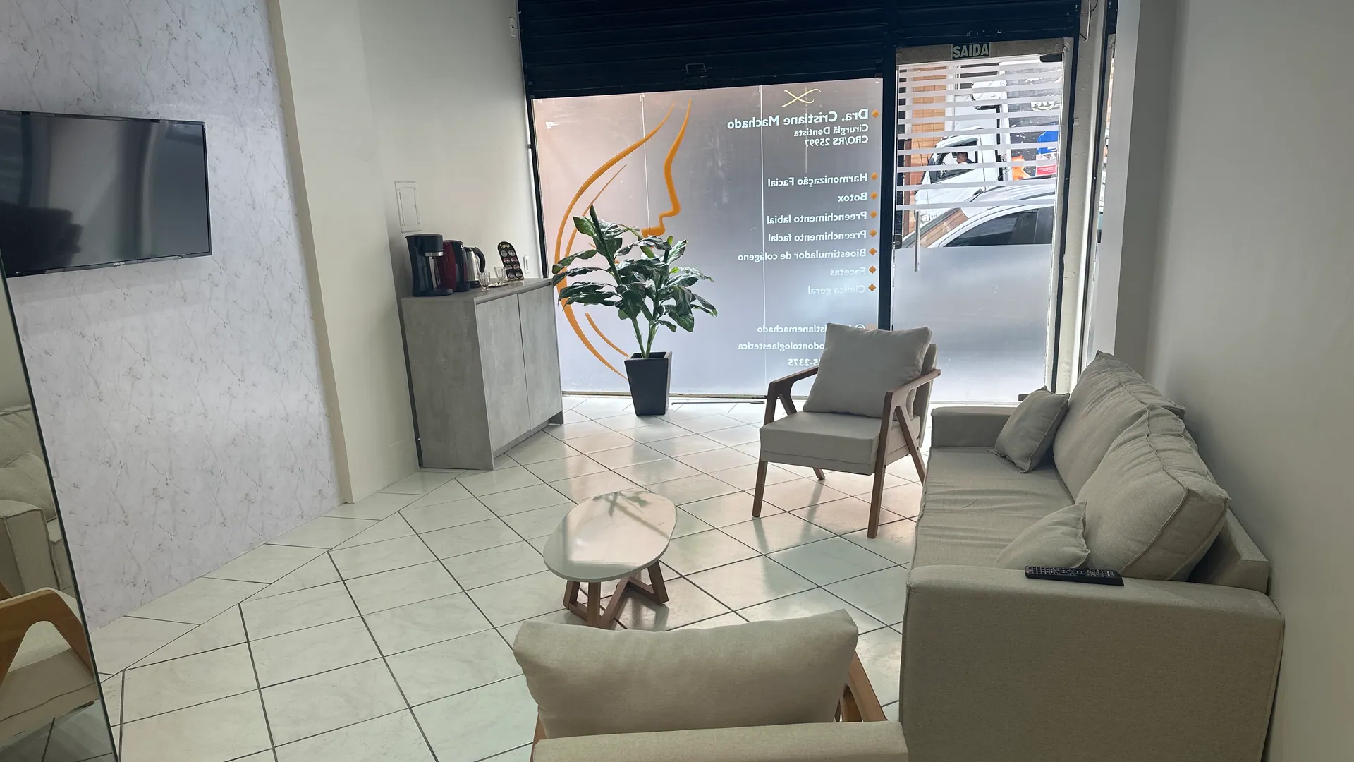 Recepção da Labella Odontologia Estética, com sofás e porta de vidro